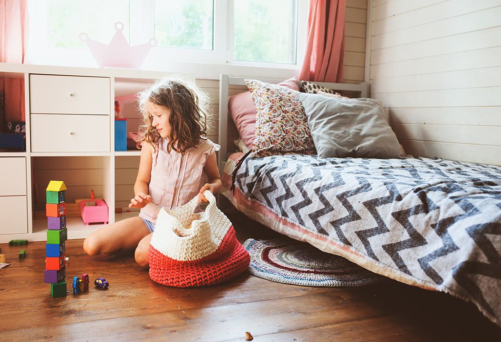 Girl organizing toys in a cozy bedroom with colorful stackable blocks on the floor