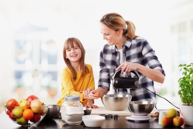 Mother and daughter baking together in a bright kitchen with fresh ingredients