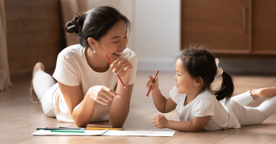 Mother and daughter drawing together on the floor, smiling and enjoying quality time