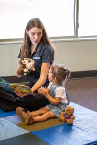 Stepping Stone School teacher reading to a young child and using a puppet to teach empathy to children through storytelling