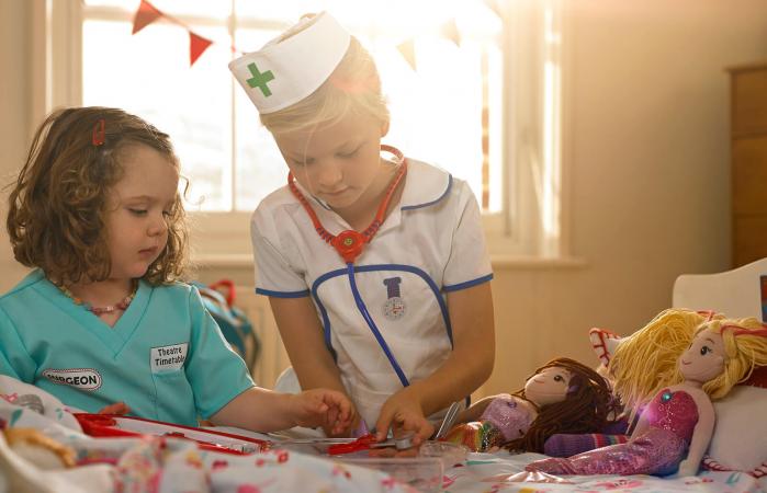 Children playing doctor and nurse with dolls in a cozy room