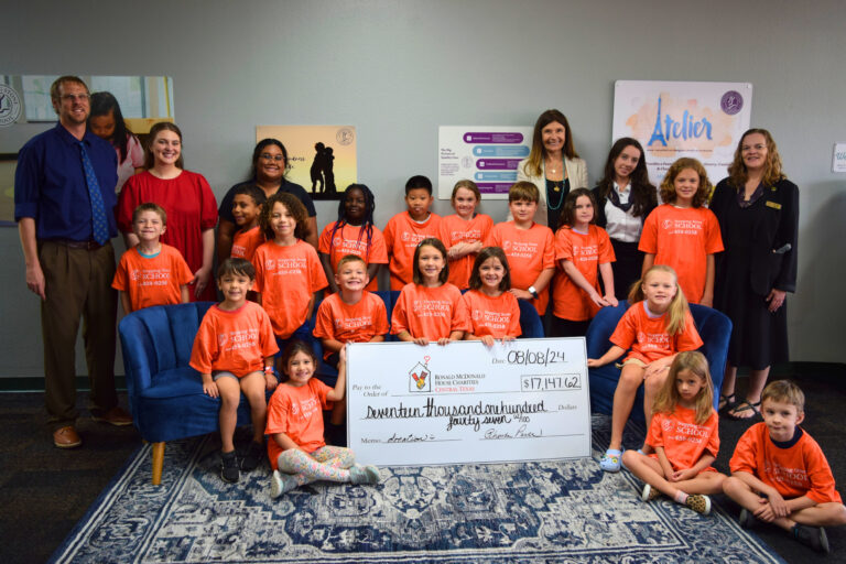 Group of children and adults holding a donation check for Ronald McDonald House Charities Central Texas