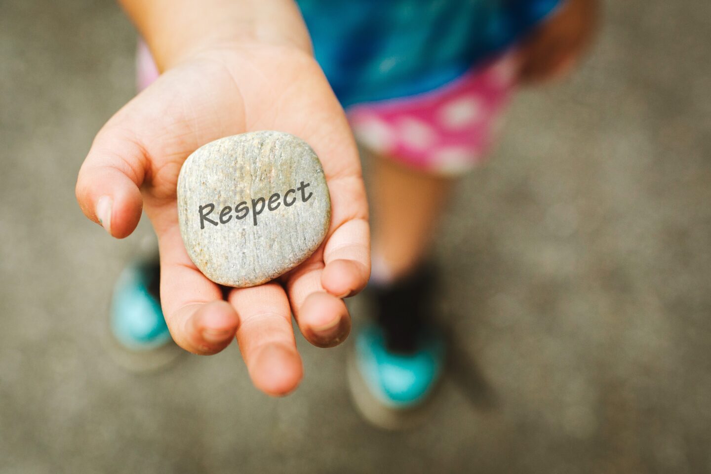 Hand holding a pebble with the word respect written on it