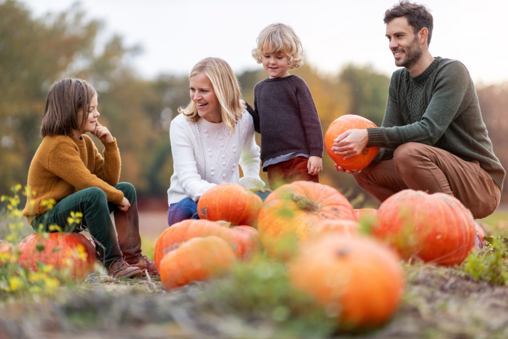 Family enjoying a day at the pumpkin patch in autumn