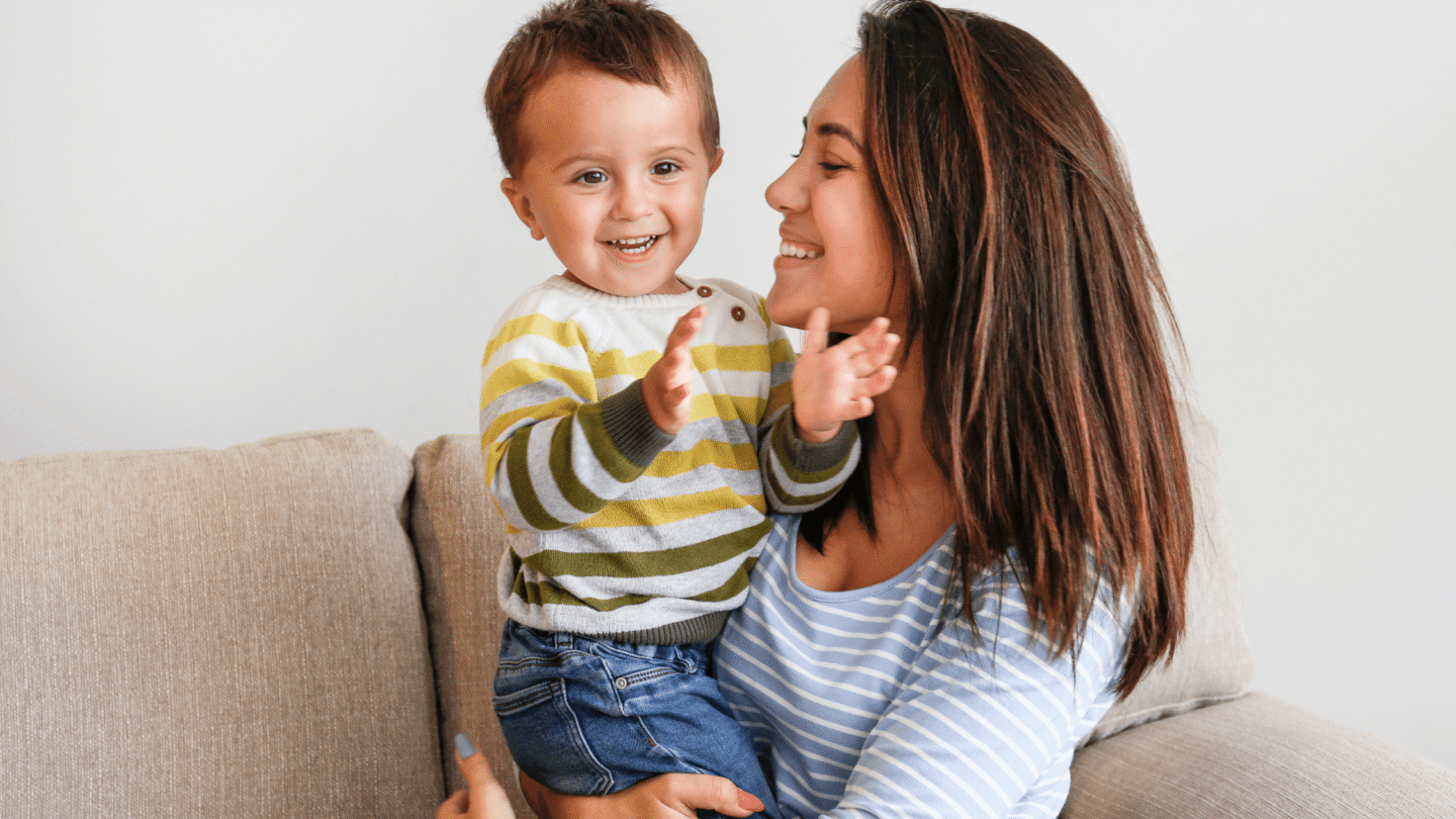 Mother and toddler smiling on couch wearing striped outfits