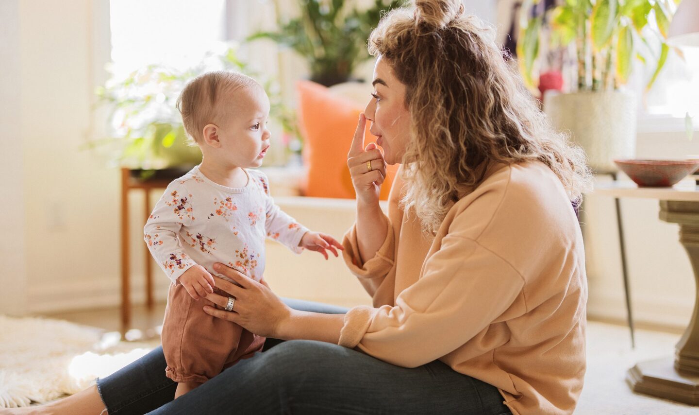 Woman playfully interacting with toddler in cozy living room setting
