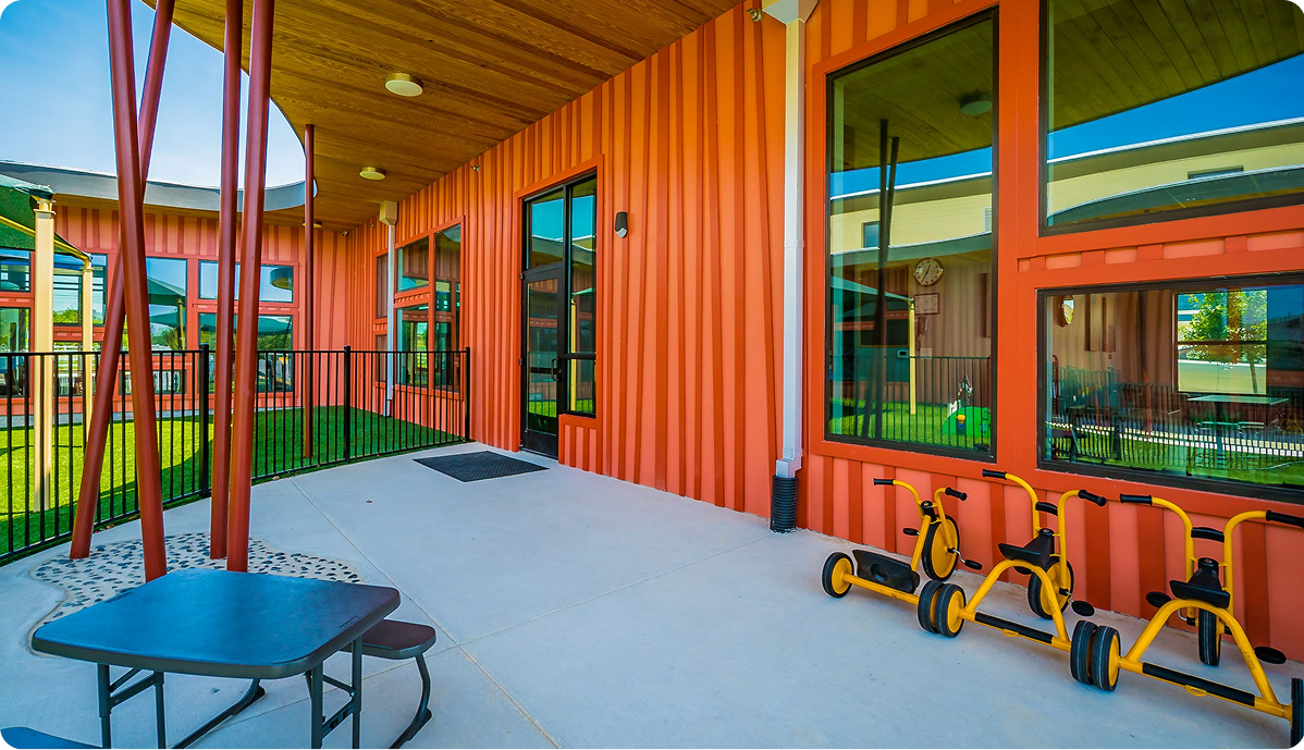 Colorful daycare playground with tricycles and bright orange building exterior