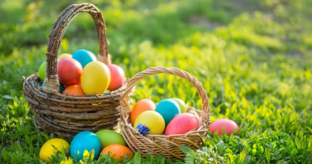Colorful Easter eggs in wicker baskets on green grass background