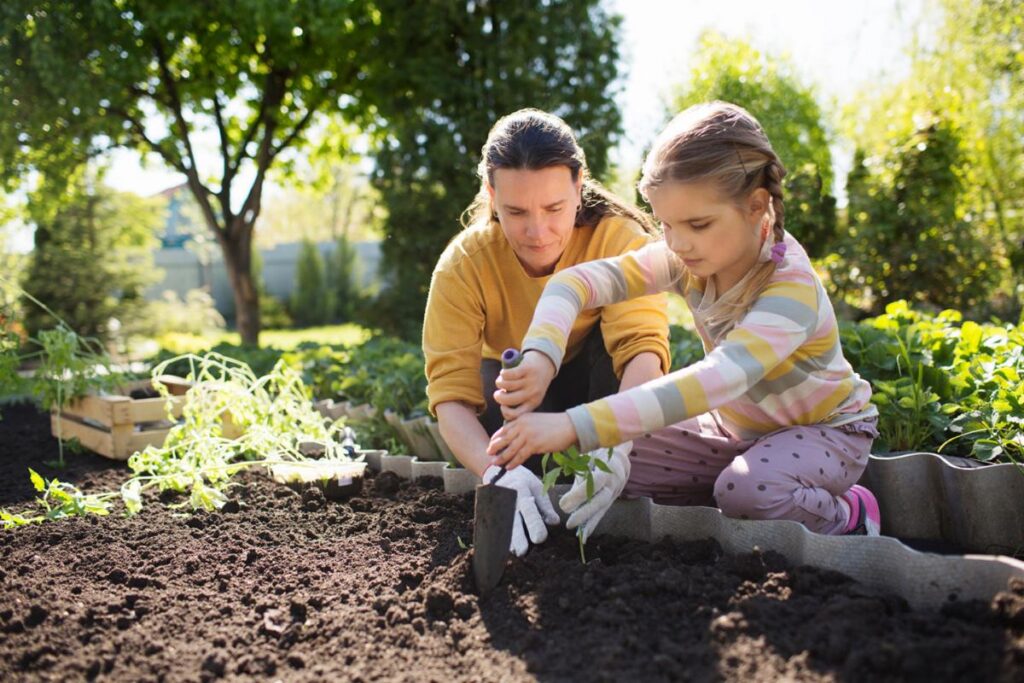 Mother and daughter gardening together on a sunny day in a lush green garden