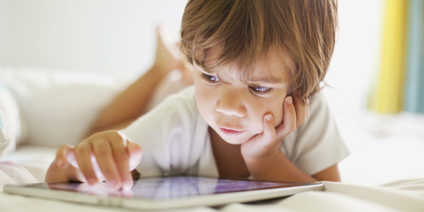Child focused on playing with a tablet in a brightly lit room