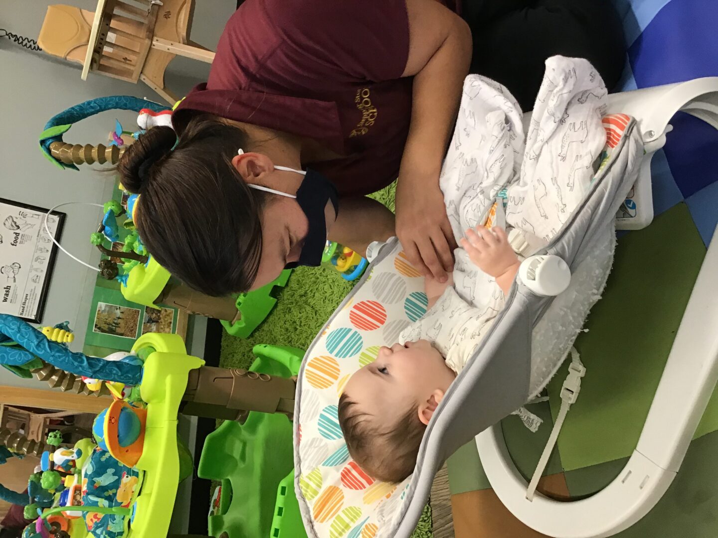 Caretaker interacting with a baby in a playroom setting