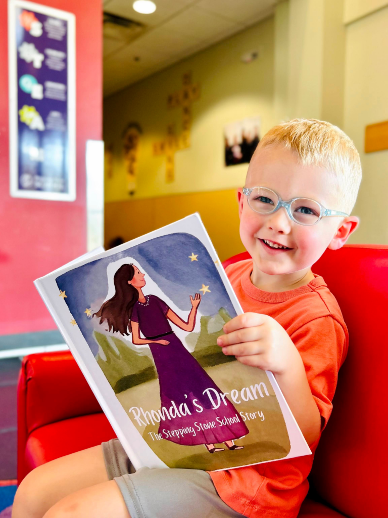 Young child with glasses reading Rhonda's Dream book in a bright room