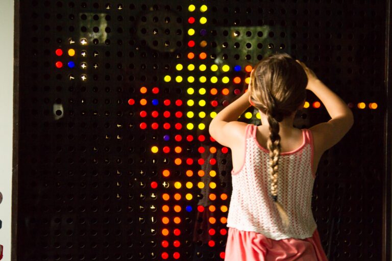 Child playing with colorful lighted pegboard wall interactive activity