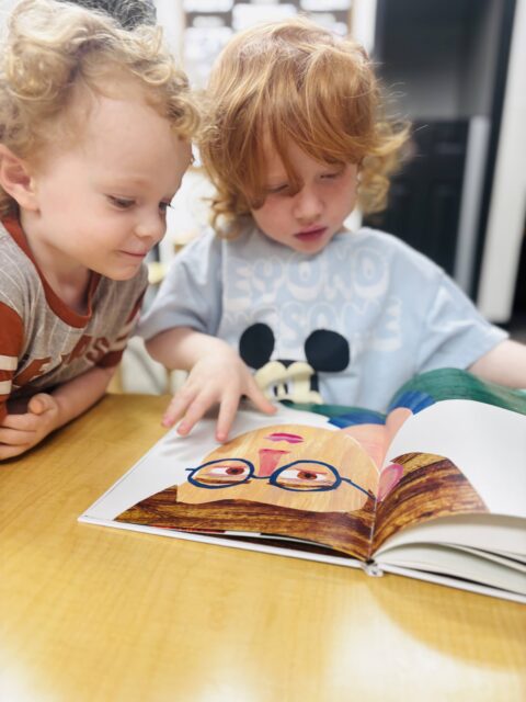 Two children reading a colorful picture book at a table