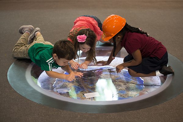 Children exploring a map exhibit on the floor while engaged in learning and discovery