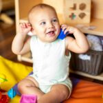 Smiling baby playing with colorful blocks on a play mat