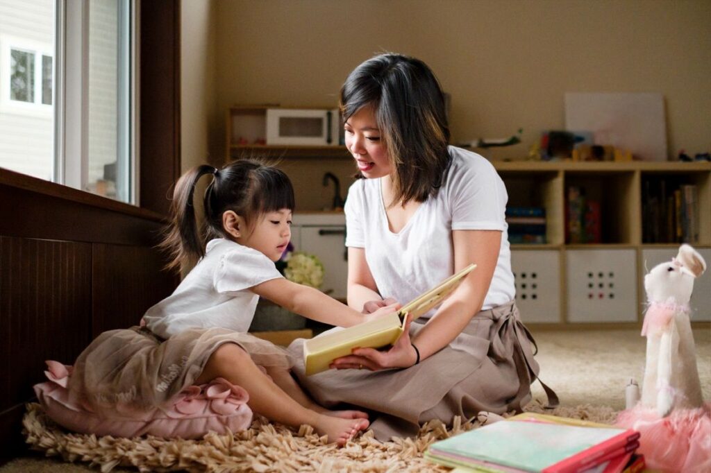 Mother and child reading a book together in a cozy living room setting