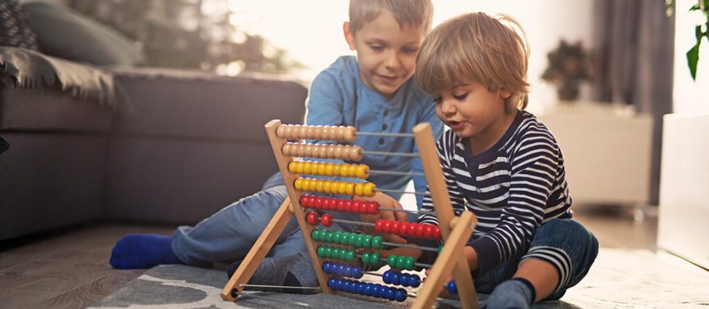 Children playing with an abacus on the floor at home