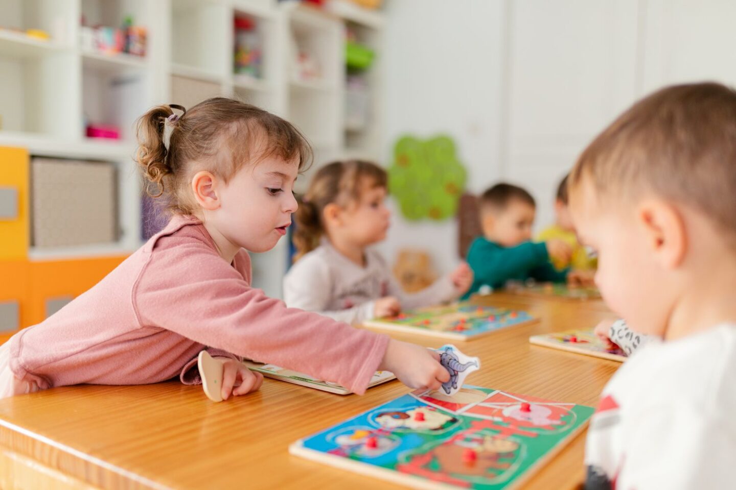 Children playing with puzzles at a classroom table