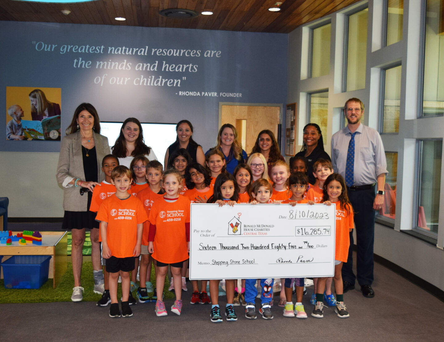Children and adults holding a large donation check at Stepping Stone School.