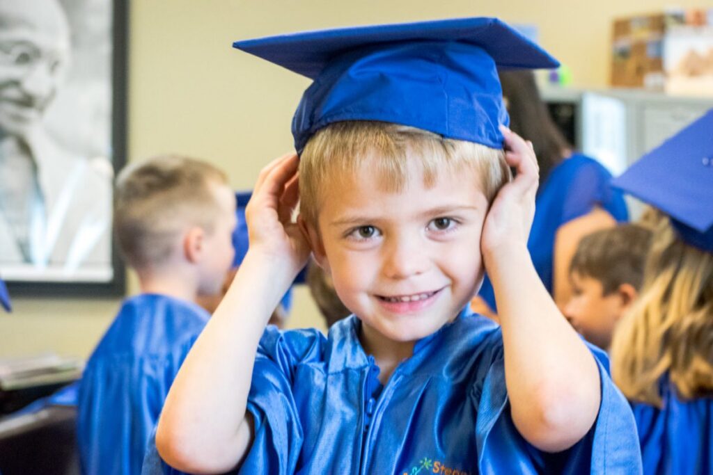 Young boy smiling in graduation cap and gown at ceremony