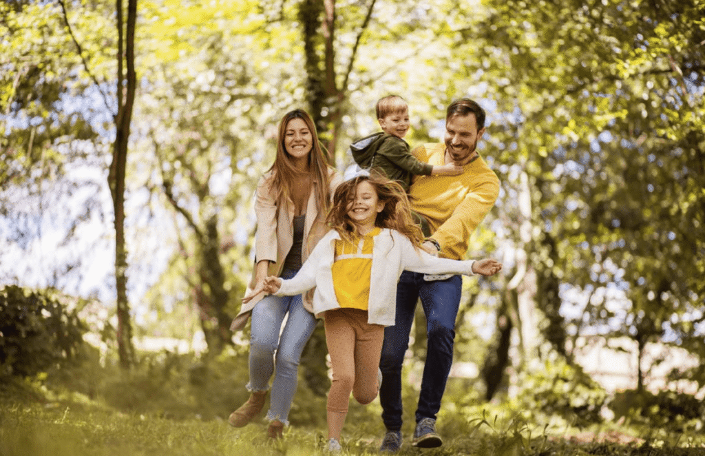 Happy family playing in a sunny park with trees in the background