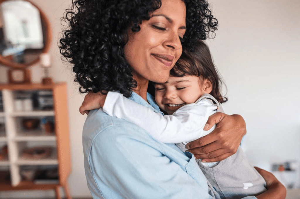 Mother hugging her smiling child lovingly at home