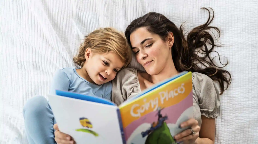 Mother and child reading a colorful storybook in bed together