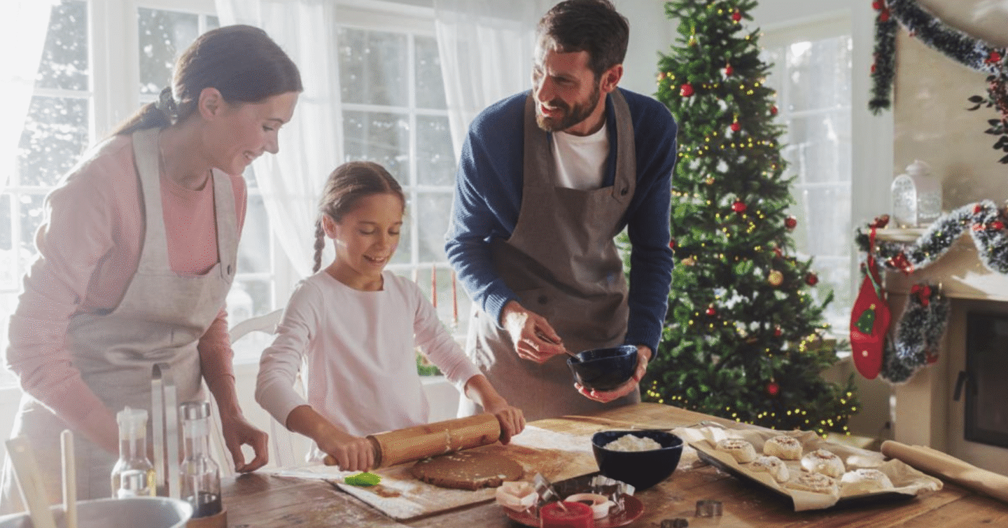 Family baking cookies together in a festive kitchen with a Christmas tree in the background