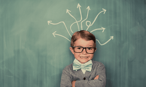 Smiling child with glasses and bow tie in front of chalkboard with arrows pointing outward