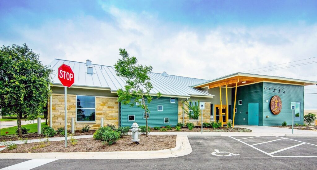 Modern building exterior with metal roof and stop sign in a landscaped setting