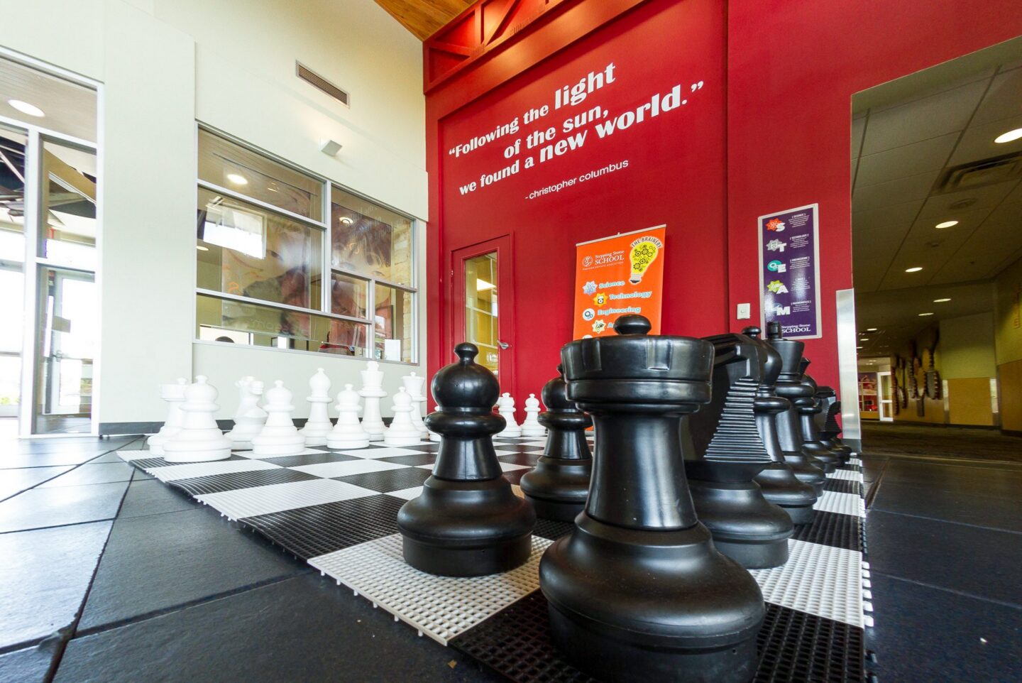 Giant chess set in a school atrium with inspirational quote on the wall