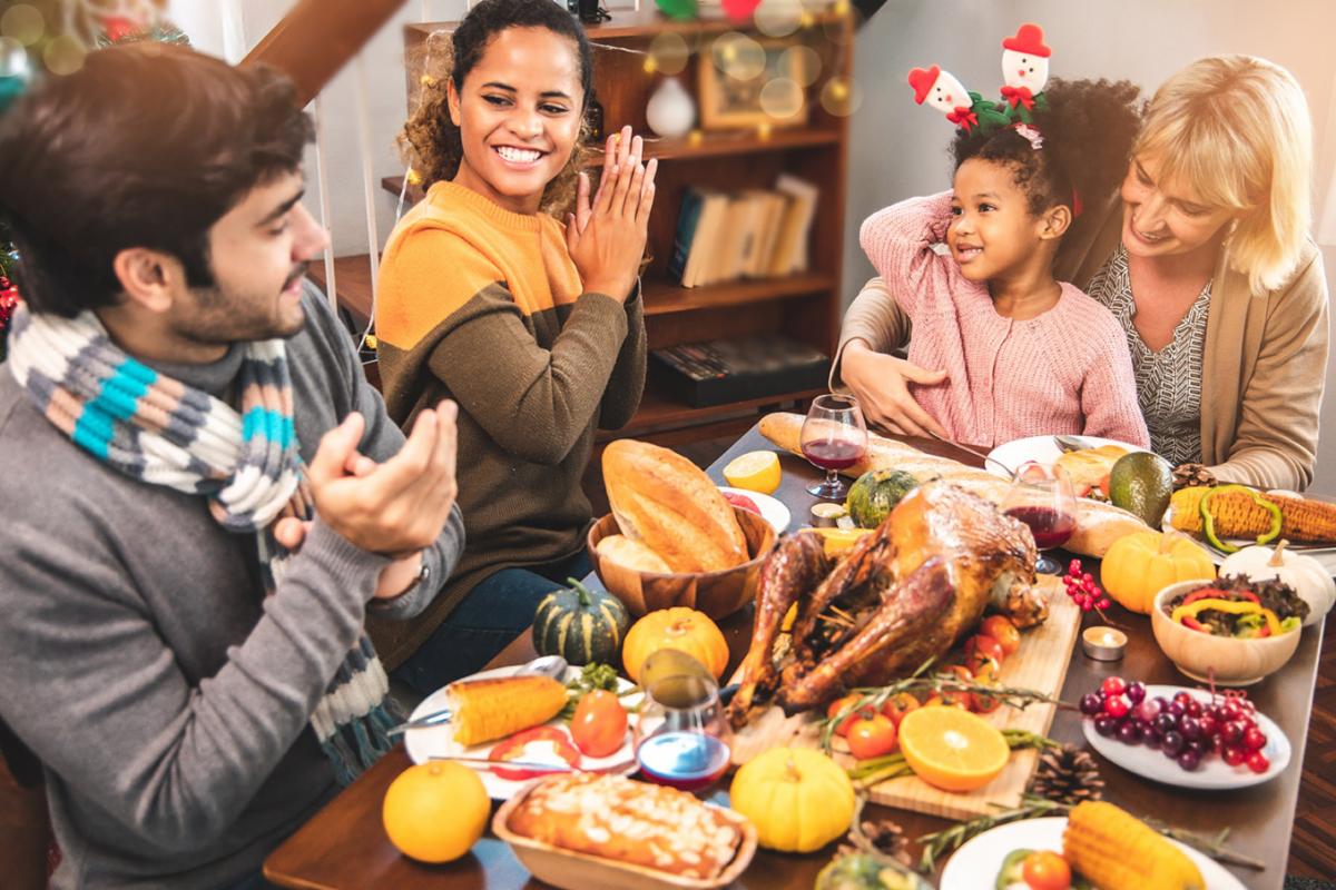 Family celebrating Thanksgiving dinner with turkey and autumn decorations