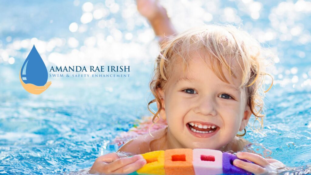 Child smiling while swimming in a pool holding a colorful floatie for safety.