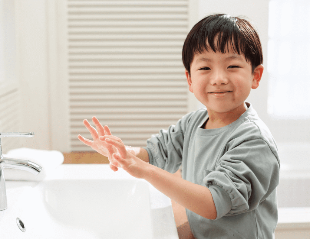 Child smiling and washing hands at a sink in a bright bathroom