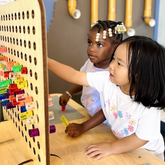 Children playing with colorful pegs on a wooden board at a learning center