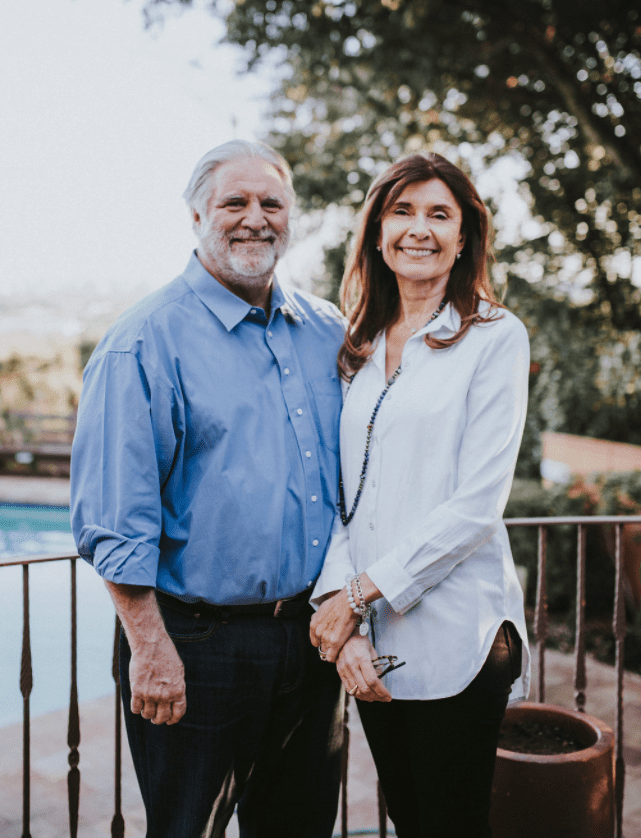 Smiling couple standing together outdoors in a garden setting