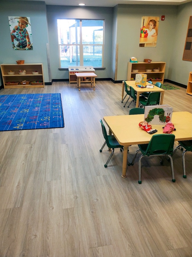 Bright preschool classroom with tables chairs and educational toys on a clean wooden floor