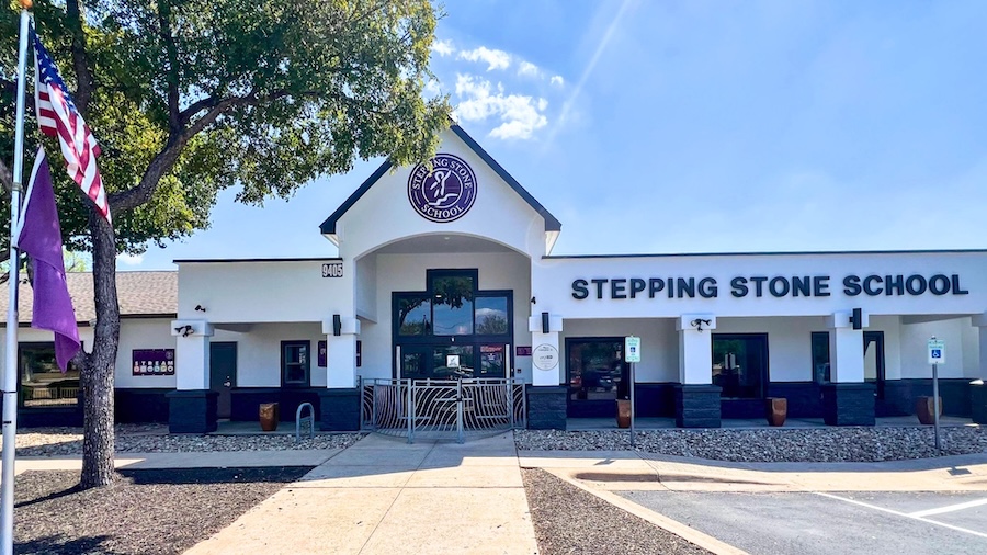 Exterior view of Stepping Stone School with flags and trees on a sunny day