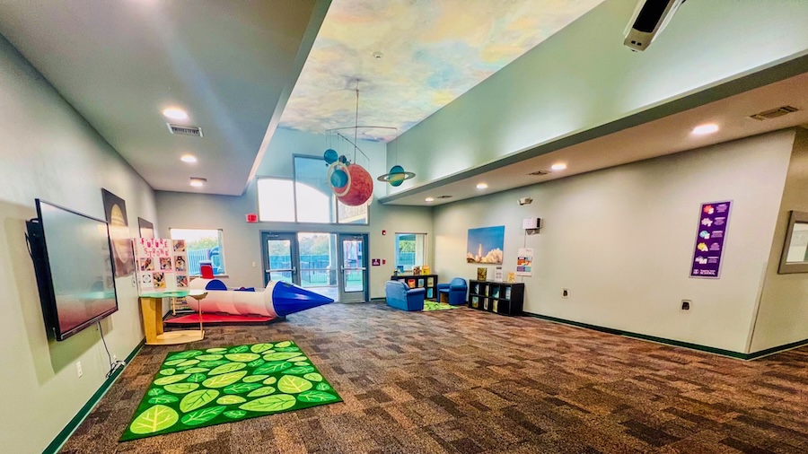 Colorful classroom with space-themed decor, rocket ship, and educational posters on the walls.