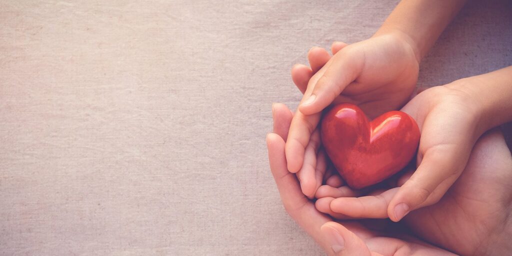 Hands holding a red heart symbolizing love and care