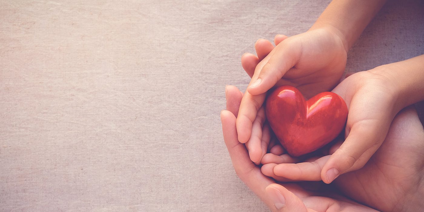 Hands holding a red heart symbolizing love and care