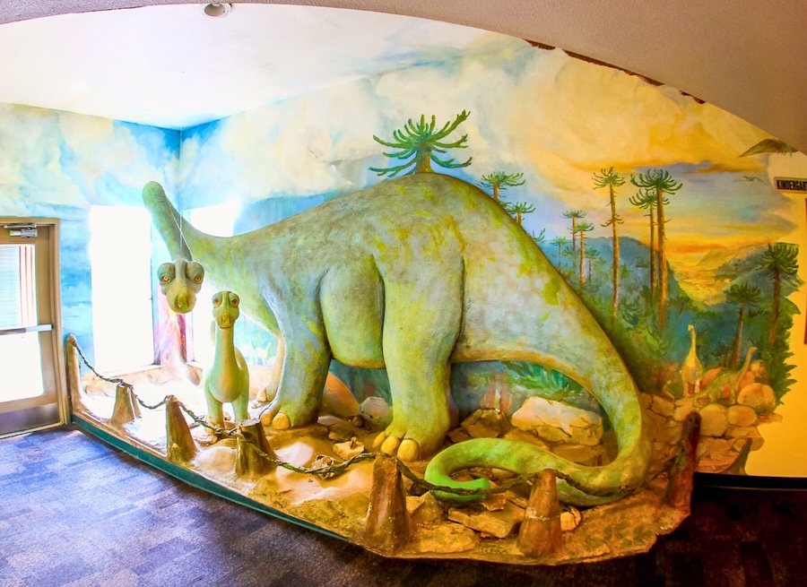 Dinosaur sculptures in a colorful prehistoric-themed room exhibit