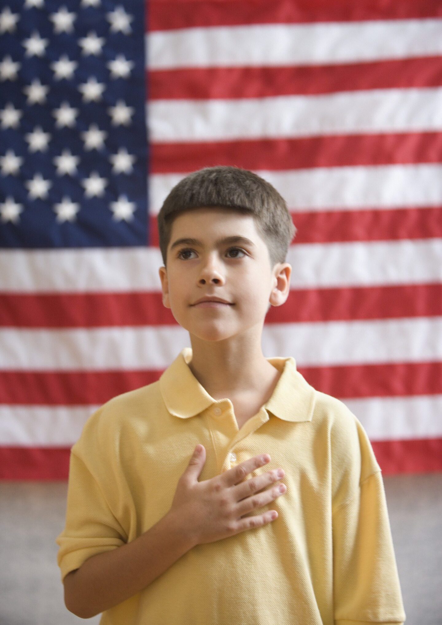 Boy in yellow shirt pledging allegiance to the American flag