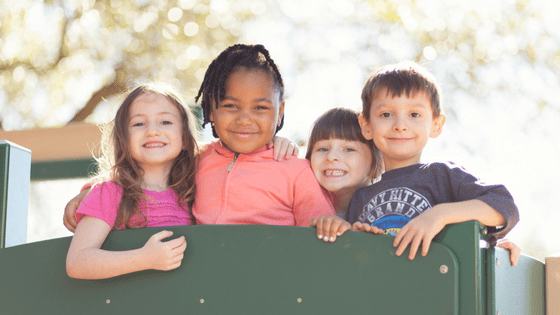 Kids smiling on a playground platform in sunny weather