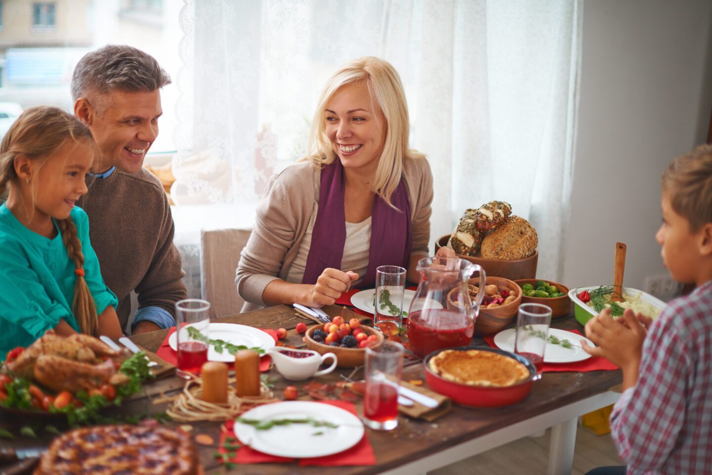 Family enjoying a festive meal together at a dining table with various dishes and drinks