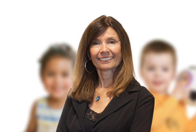 Smiling woman in a professional outfit with two blurred children in the background