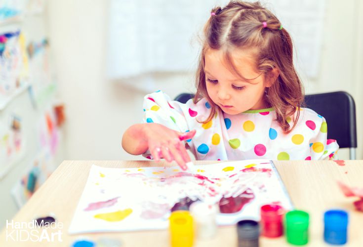 Child painting with colorful finger paints at a table in a playful environment