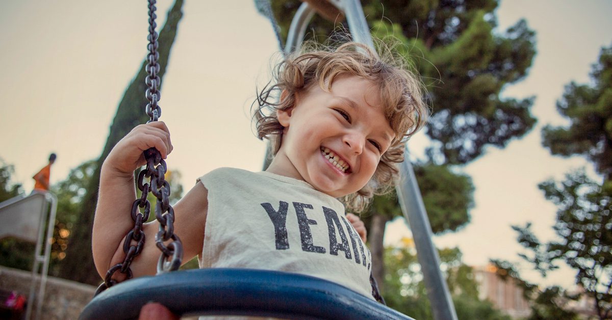 Smiling child on a swing in a sunny park