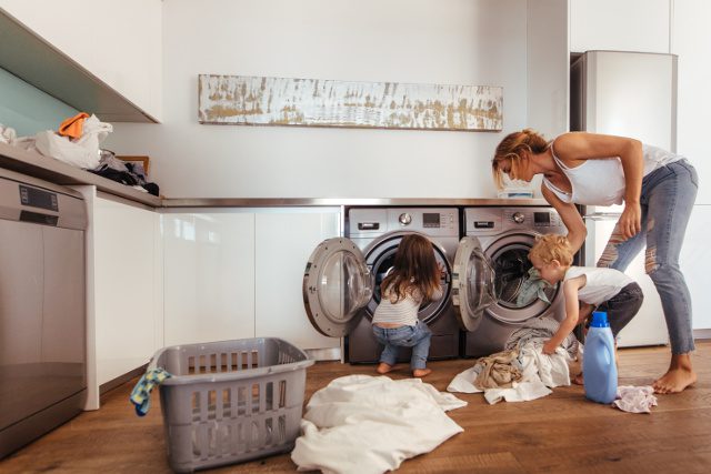 Mother and two children doing laundry together in a modern kitchen